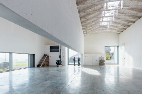 Die Wand zwischen Atelier (links) und Werkstatt ist als Betonsturz ausgebildet: So können die Hallen stützenfrei zusammengeschlossen werden. An den Stirnseiten sind Küche und Bad angeordnet.<br />