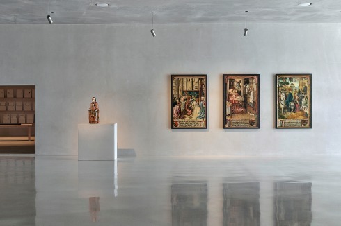Blick ins zweite Ausstellungsgeschoss. An der Wand drei Bilder aus dem Zyklus „Legende des Hl. Severin“, Meister der Ursu­la­legende und Werkstatt, Köln, um 1499–1501, Leih­gabe der Pfarrgemeinde St. Severin.<br />