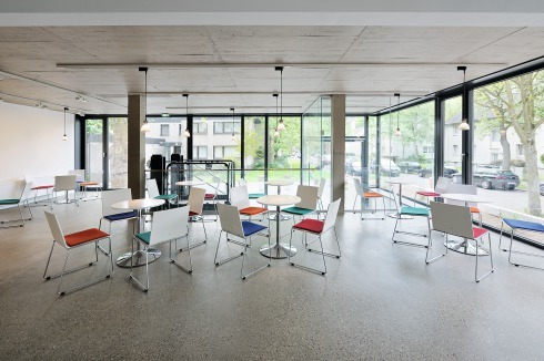 Ein winkelförmiger Anbau ergänzt den Bestand durch ein Foyer mit kleinem Café, Räume für Migrationsarbeit und Pfarrbüros.<br />