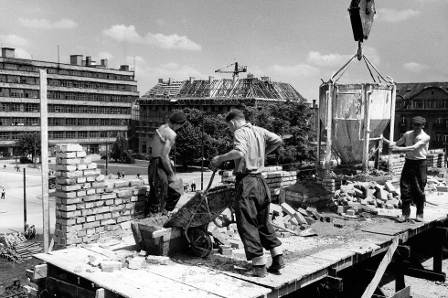 Bauarbeiten bei der Errichtung des Kościuszko-Wohn­viertels, 1955. Im Hintergrund links das nur partiell zerstörte, bereits 1948 wiedereröffnete ehemalige Kaufhaus Wertheim (Arch.: Hermann Dernburg, 1928–30)<br />