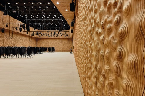 Kleiner Saal:Der konven­tionell geschnittene Saal mit 550 Plätzen ist flexibel mit einer Bühne zu gestalten und bestuhlbar. Die Auskleidung mit einem gewellten Relief aus Eichenpaneelen auch bei den Türen sorgt für eine intime Atmosphäre. Die Decke mit Pendelleuchten ist schwarz.<br />