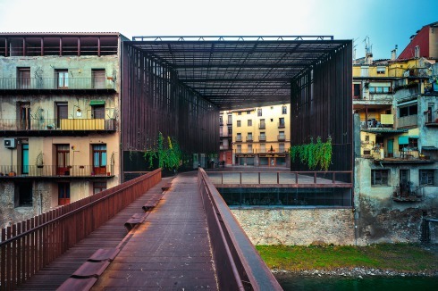 Der überdachte Platz am Ufer des Ter, mit Mehrzweckraum im Sockelgeschoss, ersetzt ein bau­fäl­liges ­Theater an selber Stelle. Zusammen mit der Fußgängerbrücke, die auch von den Architekten stammt, bildet er ein neues Tor in die Altstadt von Ripoll (2011)<br /><span class="OffWhite"></span><br />