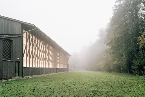 <span class="OffWhite">Der Dachüberstand ist ein von den Scheunen in Oberbayern vertrautes Motiv. Das Strebewerk vermittelt die große Fläche aus Polycarbonat zur Landschaft.</span><br />