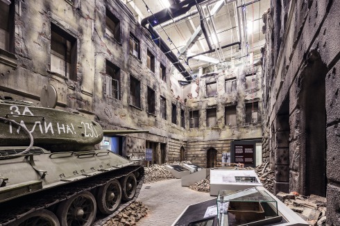Ein sowjetischer T-34-Panzer beherrscht einen Straßenraum mit den Kriegszerstörungen. Viele Säle der Ausstellung nehmen die gesamte Höhe von drei Geschossen ein.<span class="OffWhite"></span><br />