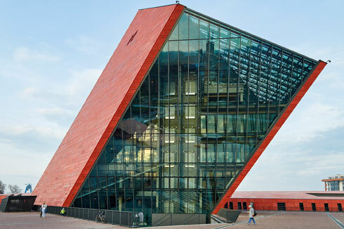 Das keilförmige Hauptgebäude setzt ein Zeichen. Jedoch ohne Bestimmung: Ob es sich aus der Erde hervorschiebt oder in sie hin­einbohrt überlassen die Architekten der Sichtweise des Betrachters.<span class="OffWhite"></span><br />