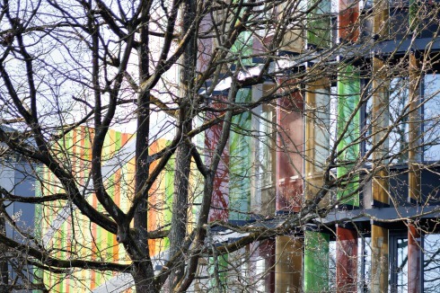 Das Äußere der Bauten wird durch Fassaden mit 2403 farbig bedruckten, drehbaren Glaslamellen zur Licht­lenkung bestimmt. Sie sind umgeben von Kiefern- und Eichenbäumen. <br />