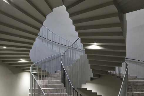 Hinter der geschlossenen Wandpartie schraubt sich die doppelläufige Treppe in die Höhe.<br />