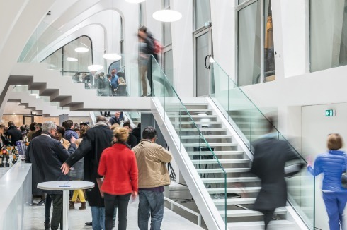 Der Besucher gelangt über neue Treppen zur unteren Ebene des offenen Foyers und nach oben in die Halle. Einheitliche Tresen passen sich den Rundungen an. <br />