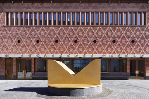 Rauten, Kreise, Rechtecke: Geometrische Formen prägen Fassaden- und Fenstergestaltung. Die goldene Skulptur mit Kerbe lässt ins Untergeschoss blicken.<br />