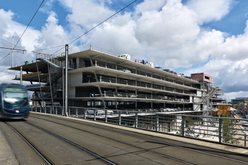 Gesamtansicht von Südosten mit den Parkterrassen und dem verglasten Erd­geschoss. Seit 2009 verbindet die Tramlinie C den Bahnhof mit dem Stadtzentrum.<br />