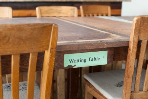 Esstisch und Stühle. "The Writing Table: Here, Like A Star, 2017. Recycled wood tables from closed Chicago Public Schools" von Bryan Saner und Teresa Pankratz<br />