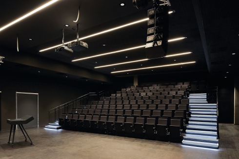 Der dunkle Hörsaal verfügt über mobile Sitzreihen und kann so auch für Ausstellungen von Videoinstallationen genutzt werden.<br />