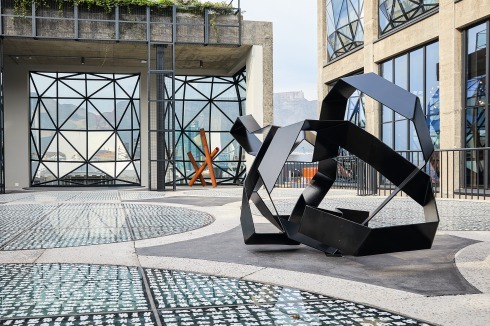 Im Skulpturengarten im 6. OG lässt sich die Zylinderstruktur erkennen. Durch den Glasboden fällt Licht ins Atrium, das aufgedruckte Mus­ter stammt von El Loko, die Skulpturen von Kyle Morland.<br />