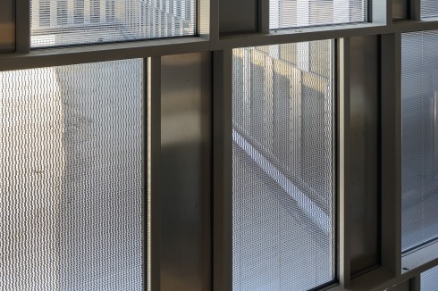 Irritation durch Abstrak­tion: Von außen scheint die Fassade kaum körperlich, sondern vielmehr eine <br />ab­strakte Grafik zu sein. Die trotz aller avancierter Minimierung immer noch notwendige Konstruktionstiefe ist nur Innen zu sehen.<br />