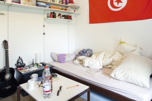 Ein Bettgestell, ein Tisch und ein Regalsystem gehören zur Grundausstattung der Wohnheimzimmer. Dennoch schaffen die Studenten in­dividuelle Räume durch persönliche Gegenstände.<br />