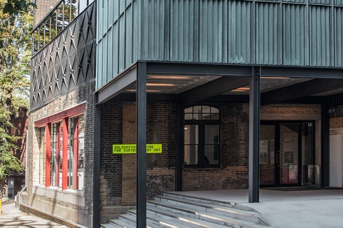 Dem Haupteingang, vis-à-vis des Visual Arts Gebäudes, lagert ein neuer Ausstellungskubus einen überdachten Pufferraum vor.<br />