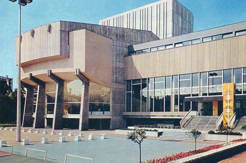 Das Foto links aus den siebziger Jahren zeigt die frühere Ansicht mit der als Parkhaus genutzten Sockelebene und der Freitreppe zum Eingang.<br />