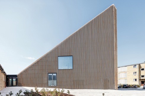Die Fassade mit ihren stab­artigen Elementen ordnet sich in Farbe und Material in die Umgebung ein.<br />