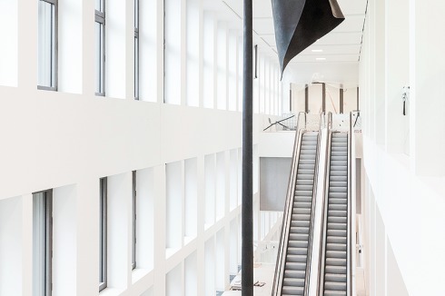 Nach dem Großen Foyer schließt die Treppenhalle mit den Rolltreppen zu den Museen an. Das Kunstwerk „Statue of Limitations“ ist vom Ai-Weiwei-Schüler Kang Sunkoo.<br />