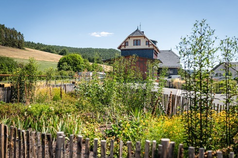 Kleine „Bauerngärten“ mit regionaltypischer Umzäunung begrünen den Außenraum des Bahnhofs.<br />