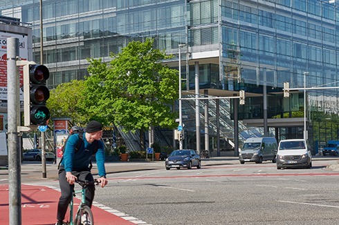 Verflochten und verdreht: ein Radfahrer auf der his­torisch autogerechten Verkehrskreuzung des Aegidientorplatzes und der gläserne Komplex der Nord/ LB, entworfen von Behnisch Architekten.<br />