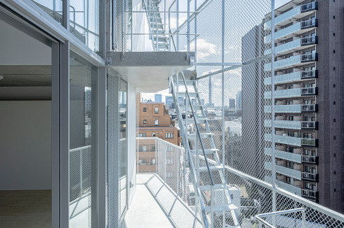 Eine Mischform aus Laubengang und schräg auskragender Balkon erschließt an der Vorderseite die neun Geschosse des Hauses.<br />