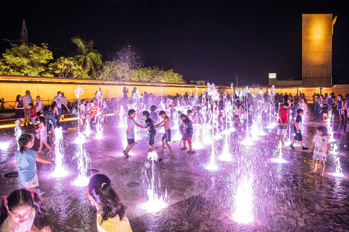 Auf dem „Platz der Lichter“ spielen Kinder in den Wasserfontänen der Sprinkleranlage.<br />