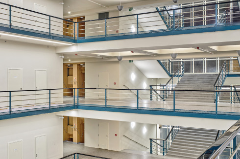 Auf der Galerie ist Schwindelfreiheit nötig – Blick von Etage 3 ins Atrium und auf die Freitreppe. Neben den Paternostern schließen die Flure der Büroflügel an.  <br />