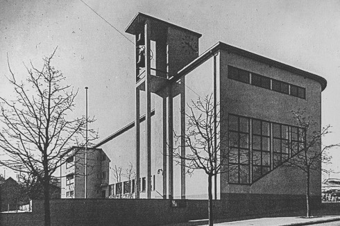 Die Kirche entstand zwischen Bauhaus- und traditionalistischer Siedlung.  Als Ende der 1960er der Verkehr um sie herum zunahm, stand ein Abriss im Raum.<br />