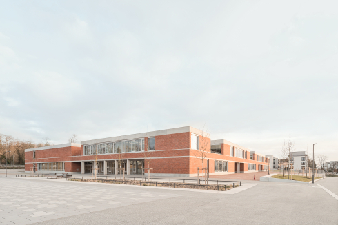 An den schmalen Seiten liegen die Eingänge: Vom Quartiersplatz aus geht es in die Grundschule, gegenüber an der Erschließungsstraße in die Kita.<br />