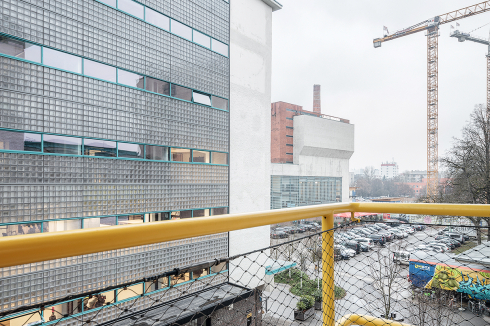 ... auf das Haus Havanna (im EG die ROSE) und den Peter-Behrens-Platz mit Kraftwerk, dahinter Kran der Hochhaus-Baustelle<br />