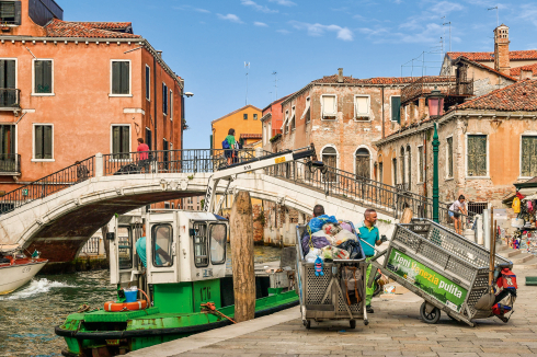 „Tieni Venezia pulita“ – Halten Sie Venedig sauber. Wo viele Menschen zusammenkommen, ist Sauberkeit eine Sisyphosarbeit. Damit Müllsäcke den öffentlichen Raum der Touristenstadt nicht verschandeln, müssen sie zu Sammelbooten gebracht werden; oder man wartet auf die Straßenreinigung, die die Säcke an der Tür abholt.<br />