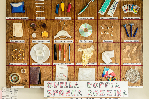 Ein Brett zeigt 24 „Designfehler“, darunter steht auf italienisch „Das doppelte Dutzend Dreck“.<br />