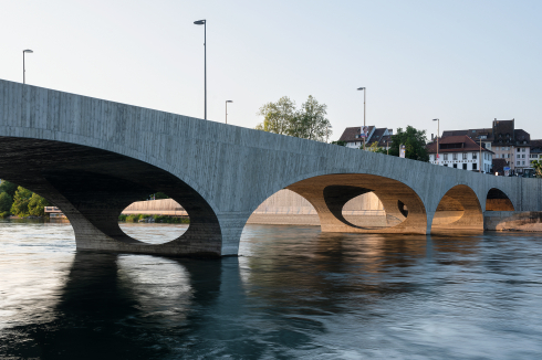 Die neue Aarebrücke überspannt mit drei Bögen aus Stahlbeton den Fluss, an den Ufern kommt je ein weiterer hinzu. Die Öff­nungen in den Bögen neh­men dem Raum unter der Brücke die Bedrohlichkeit.<br />