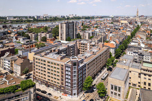 Blick nach Norden über den Stadtteil Sint-Andries. Die Fierenshöfe bestehen aus einem großen Wohnblock (Vordergrund) und einem L-förmigen Gebäude im westlichen Nachbarblock (verdeckt). Links: Hofzufahrt an der Westseite. Grundriss: Obergeschoss zweier neuer Maisonette-Wohnungen.<br />