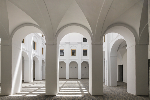 Reduktion auf weiße Tünche und Naturstein schärft die Aufmerksamkeit für feine Unterschiede der Fassade. Im ersten Hof heißt flirrendes Licht willkommen.<br />