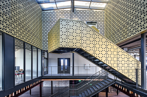 Die perforierte Aluminiumhaut, die als gefaltete Schale den Konturen des Bestandsgebäudes folgt, soll als eine zeitgenössische Interpretation der Architektursprache des Speichers wahrgenommen werden.<br />