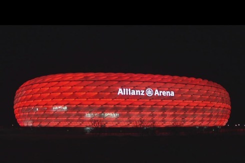 Die Münchner Allianz Arena leuchtet in der Nacht zur Autobahn herüber.<br />