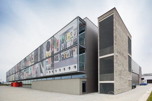 Die mit textilen Bildtafeln bespannte Westfassade macht deutlich, dass es sich hier mitnichten um eine <br />Lagerhalle handelt<br />