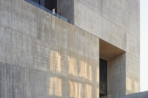 Im Vergleich zu den Einschnitten und Auskragungen, wirkt der Eingang in der massiven Fassade winzig<br /><br />