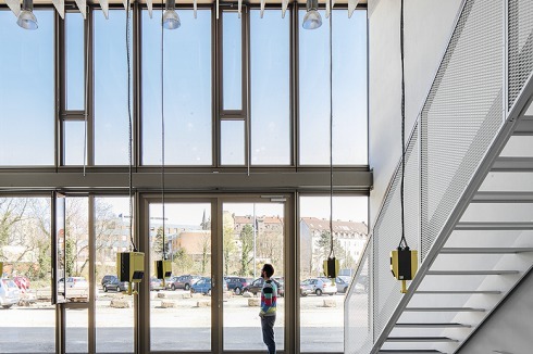 Zweigeschossiges Atelier mit Aufgang zur Galerie. Rechts: Ein Passepartout aus Sichtbeton rahmt den Haupteingang<br />