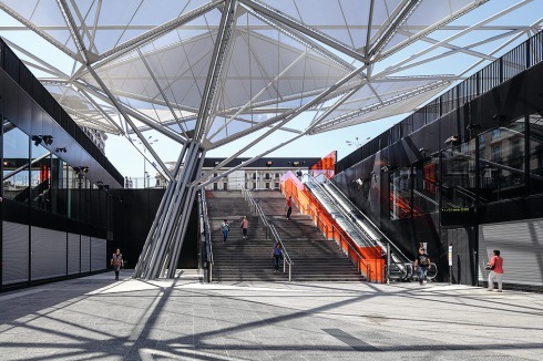 An den kurzen Seiten führen Treppen und Rolltreppen zum Platz hinauf, seitlich sind weitere Aufgänge eingefügt<br />