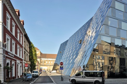 Auf der Westseite der Bibliothek, zur Milchstraße, wird der Stadtraum negiert. Im Hintergrund das Stadttheater. Im Erdgeschoss drohen Beschädigungen der Fassade durch parkende Autos.<br />