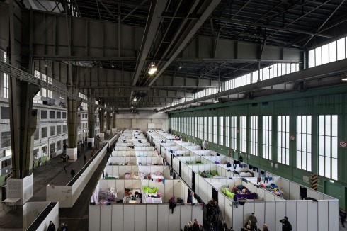 Pressetermin, Anfang Dezember, im ehemaligen Flughafen Berlin-Tempelhof: In den Hangars des ehemaligen Flughafens sind 2000 Flüchtlinge untergebracht. Unter der gewaltigen Konstruktion Ernst Sagebiels trocknet Wäsche, die Toiletten stehen auf dem Vorplatz. Duschcontainer werden gerade installiert.<br />