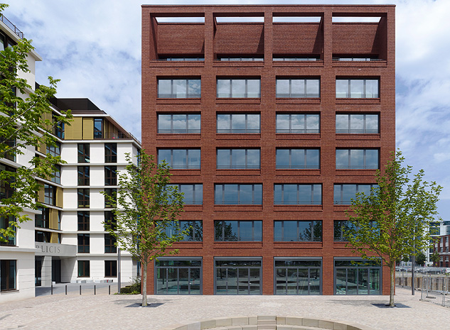 Der rote Klinkerbau sticht aus seiner Umgebung als Zentrum des Quartierplatzes hervor.