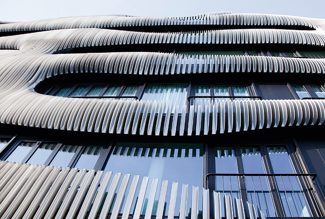Die vorgesetzte Lamellenstruktur zieht sich wie eine zweite Haut über die zurückhaltende Aluminium-Glas-Fassade.